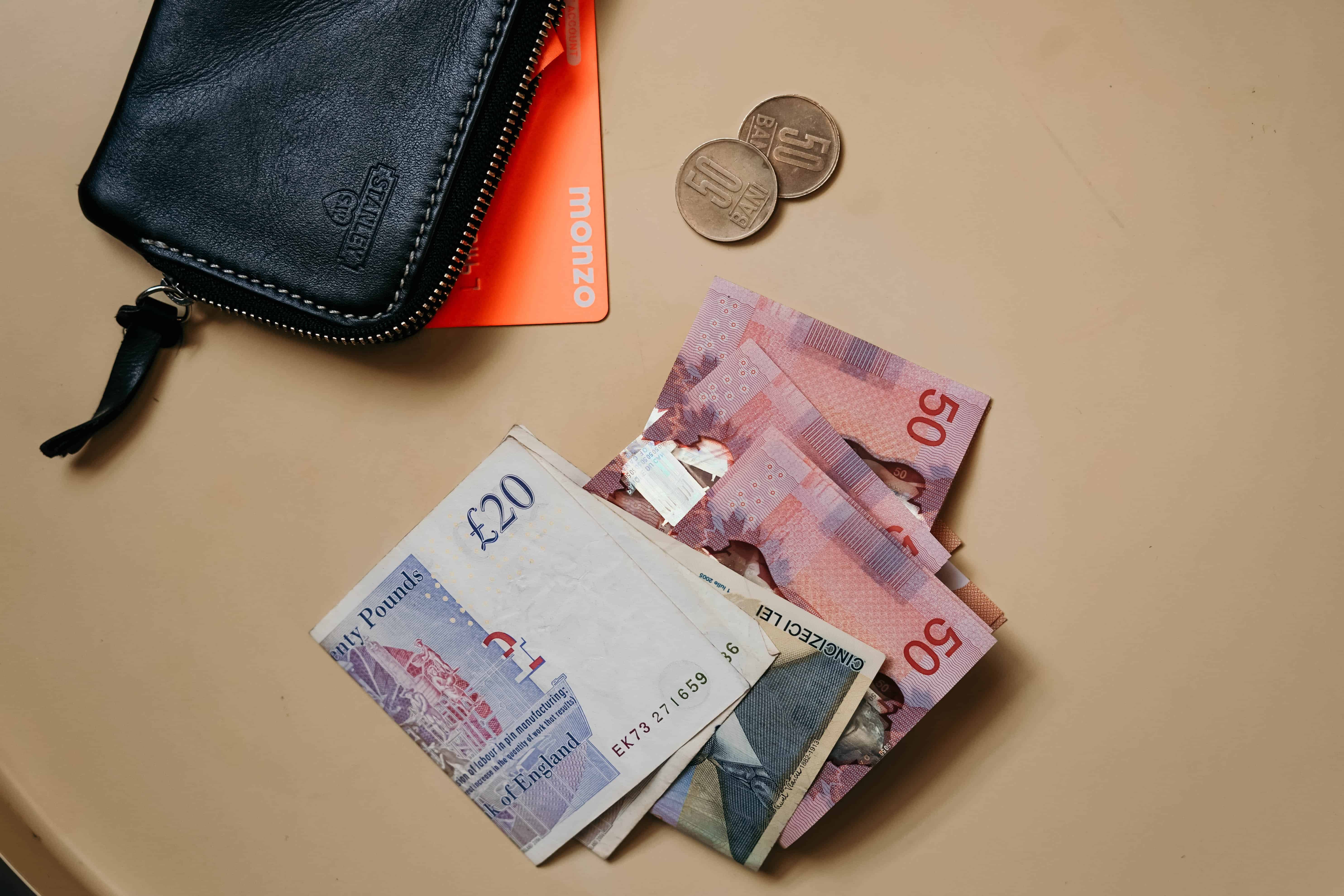 A pile of £20 notes alongside a wallet.