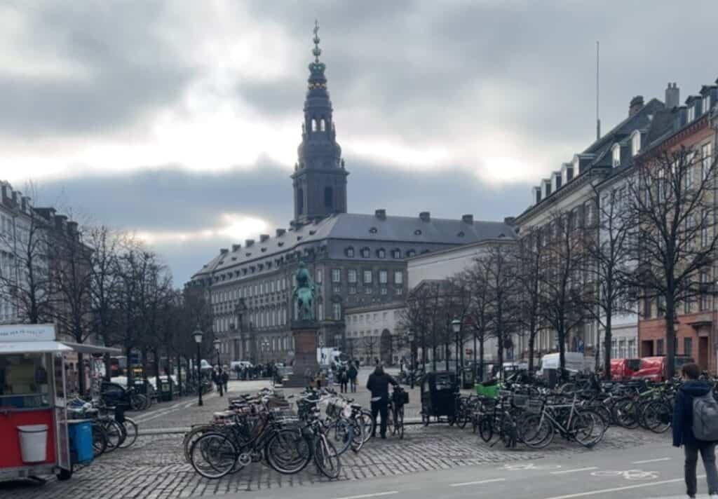 A picture of Christiansborg palace from down a street looking down to it. 