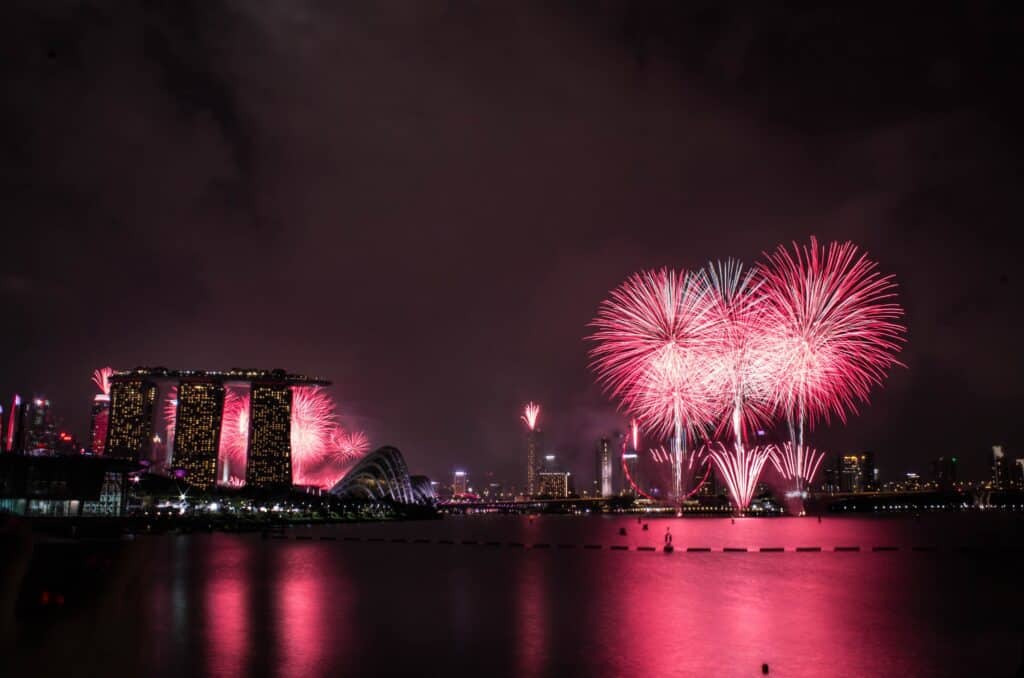 A picture of the Marina Bay at nighttime with pink fireworks over the skyline. 