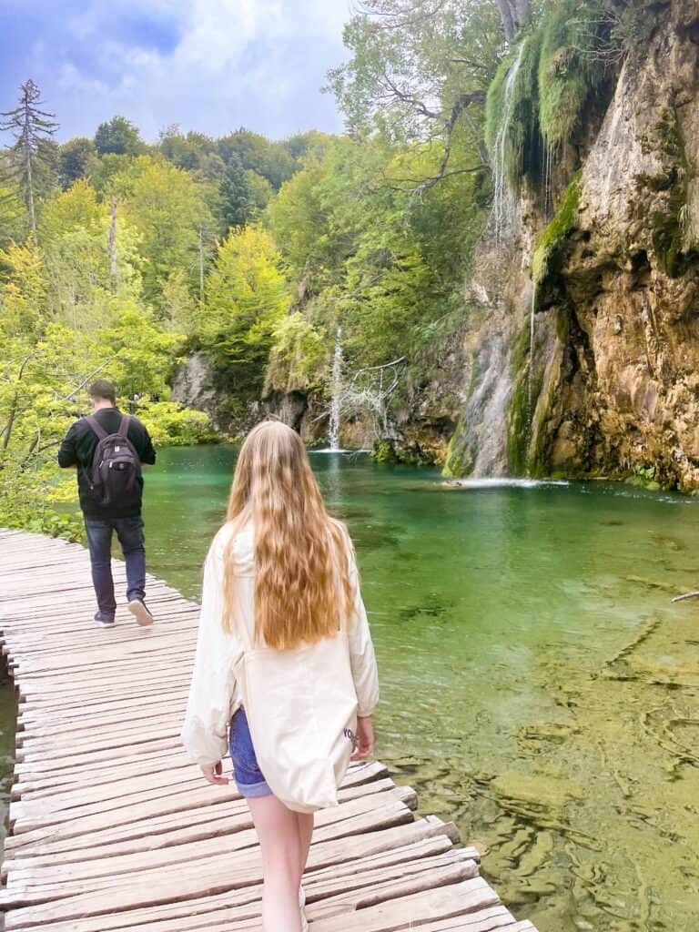 A picture of the boardwalks in Plitvice Lakes walking alongside some minor waterfalls. The close walkways are a reason to choose Plitvice over Krka.