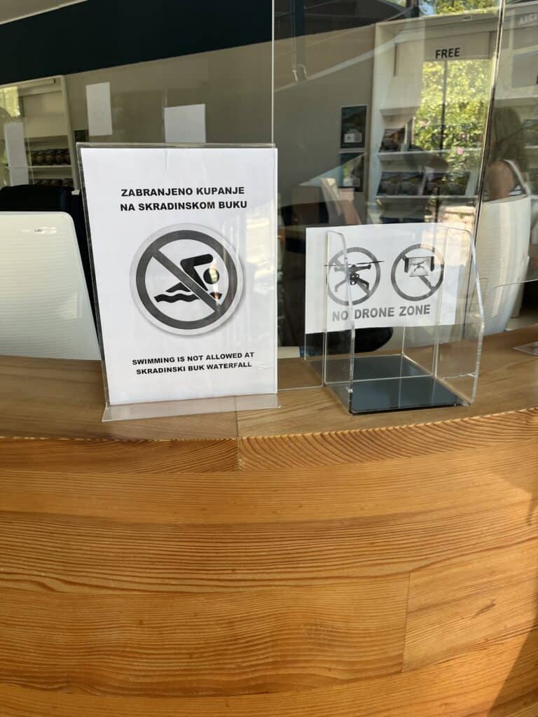 A picture of two signs showing swimming is not allowed in Krka, and it is a no drone zone.