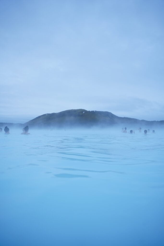 A picture taken from in the water of the Blue Lagoon showing the steam coming off the water.
