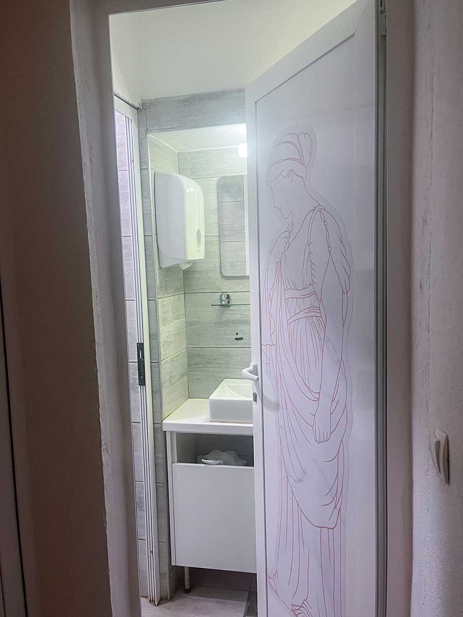 Open door to a bathroom featuring modern amenities and a door with an etched line drawing of a man in traditional attire.