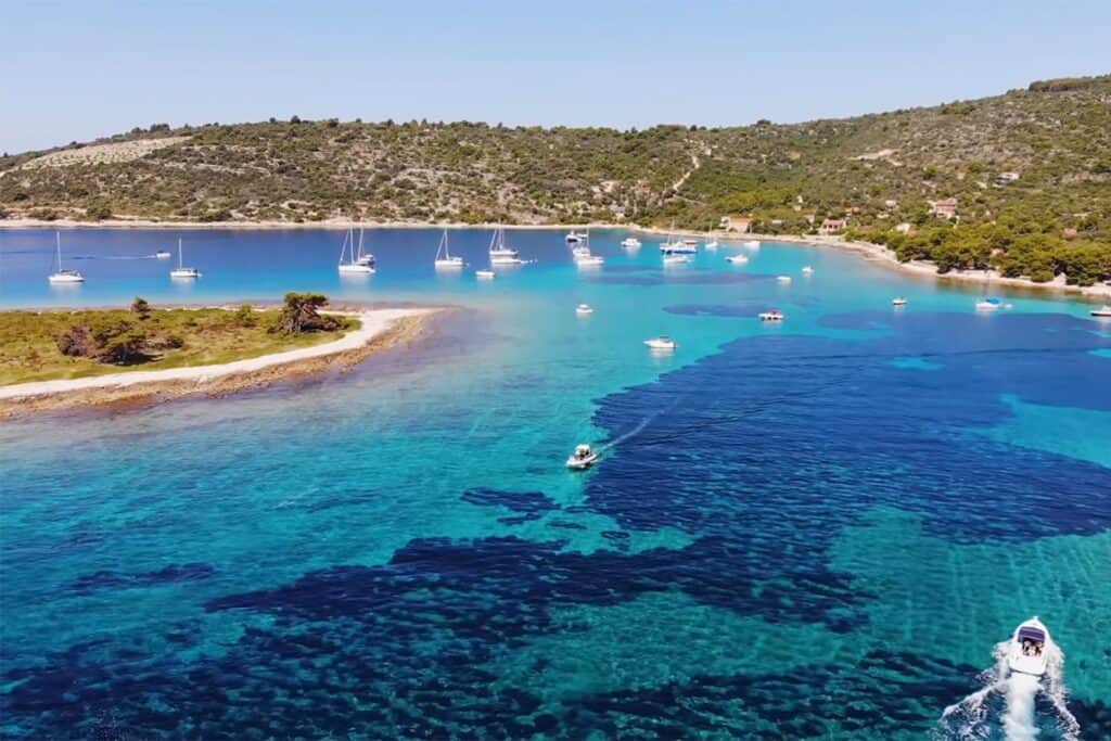 Aerial view of the Blue Lagoon in Croatia, showcasing the vibrant blue waters and moored sailing boats, highlighting the popular boating destination.