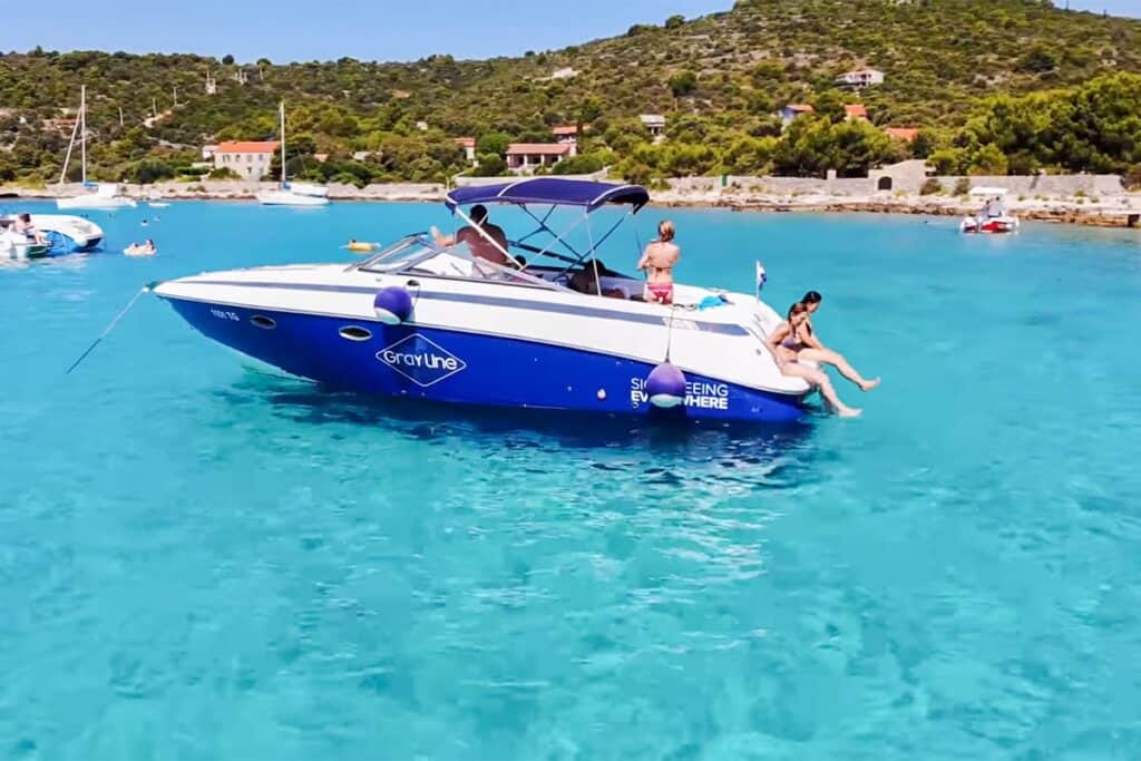 Vivid blue waters of the Blue Lagoon in Croatia with tourists enjoying a sunny day on a Gray Line tour boat, illustrating the area's recreational offerings